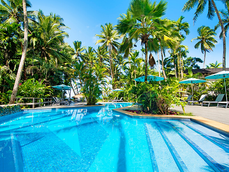 Resort pool surrounded by palm trees at ULTIQA Fiji Palms Beach Resort.