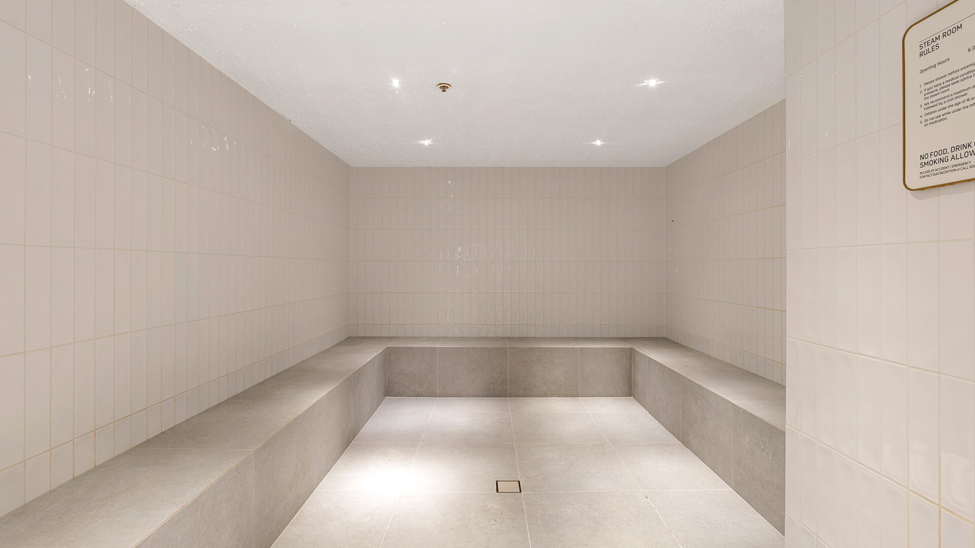 Bright tiled steam room with built-in bench seating at ULTIQA Signature.