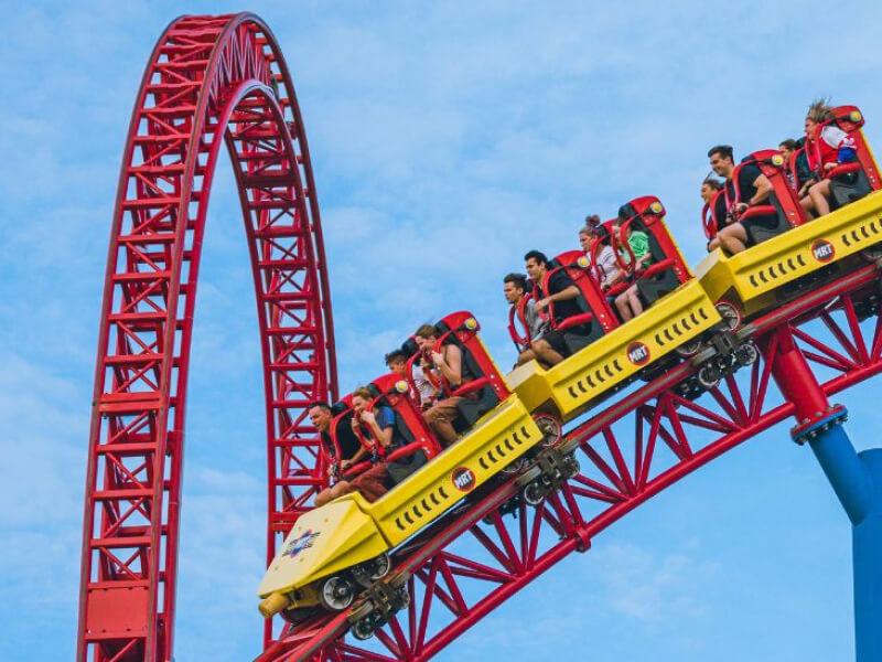 People riding a high-speed roller coaster at a Gold Coast theme park, smiling and enjoying the thrill.