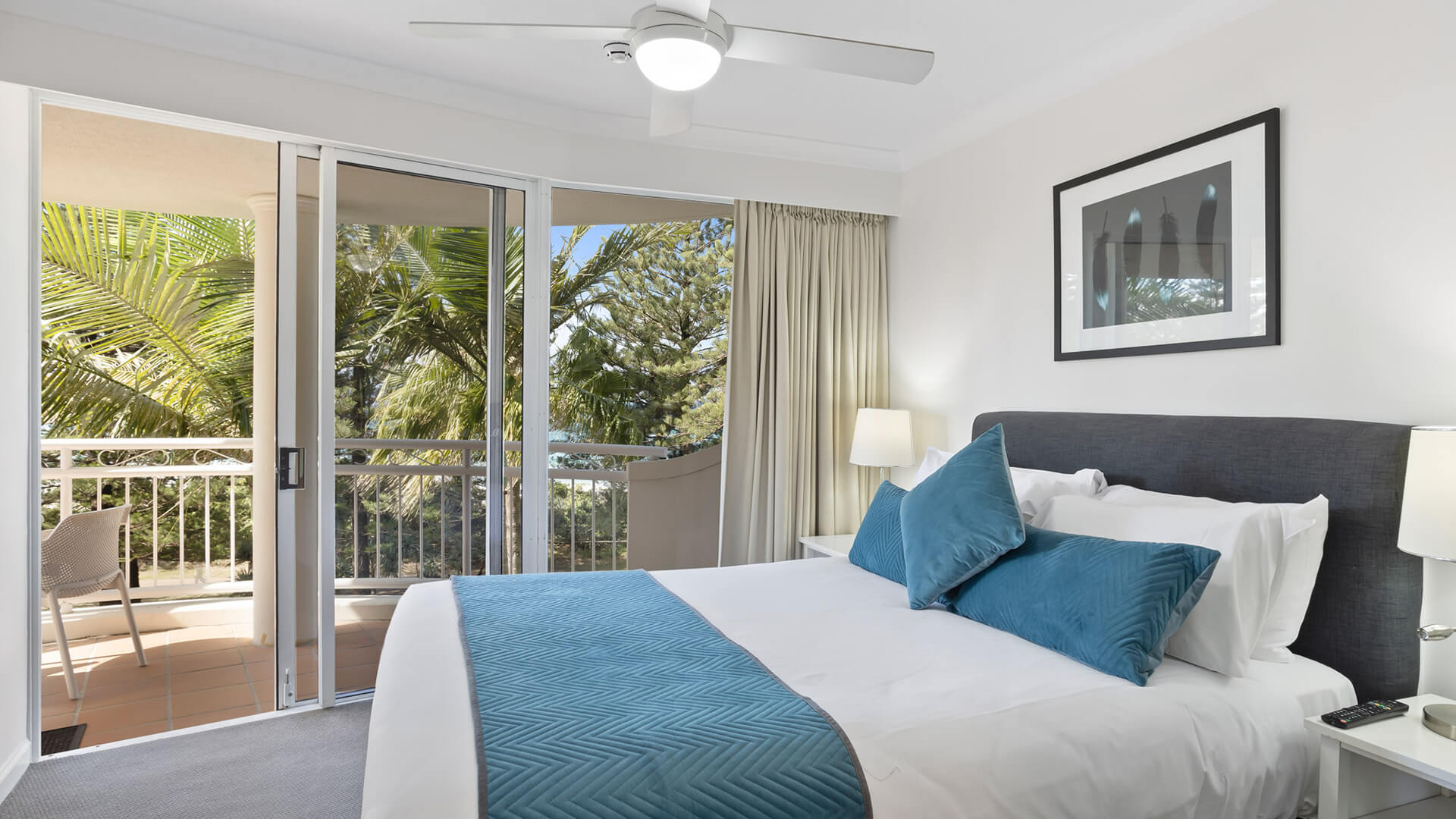 Bright bedroom with balcony access and tropical garden views.