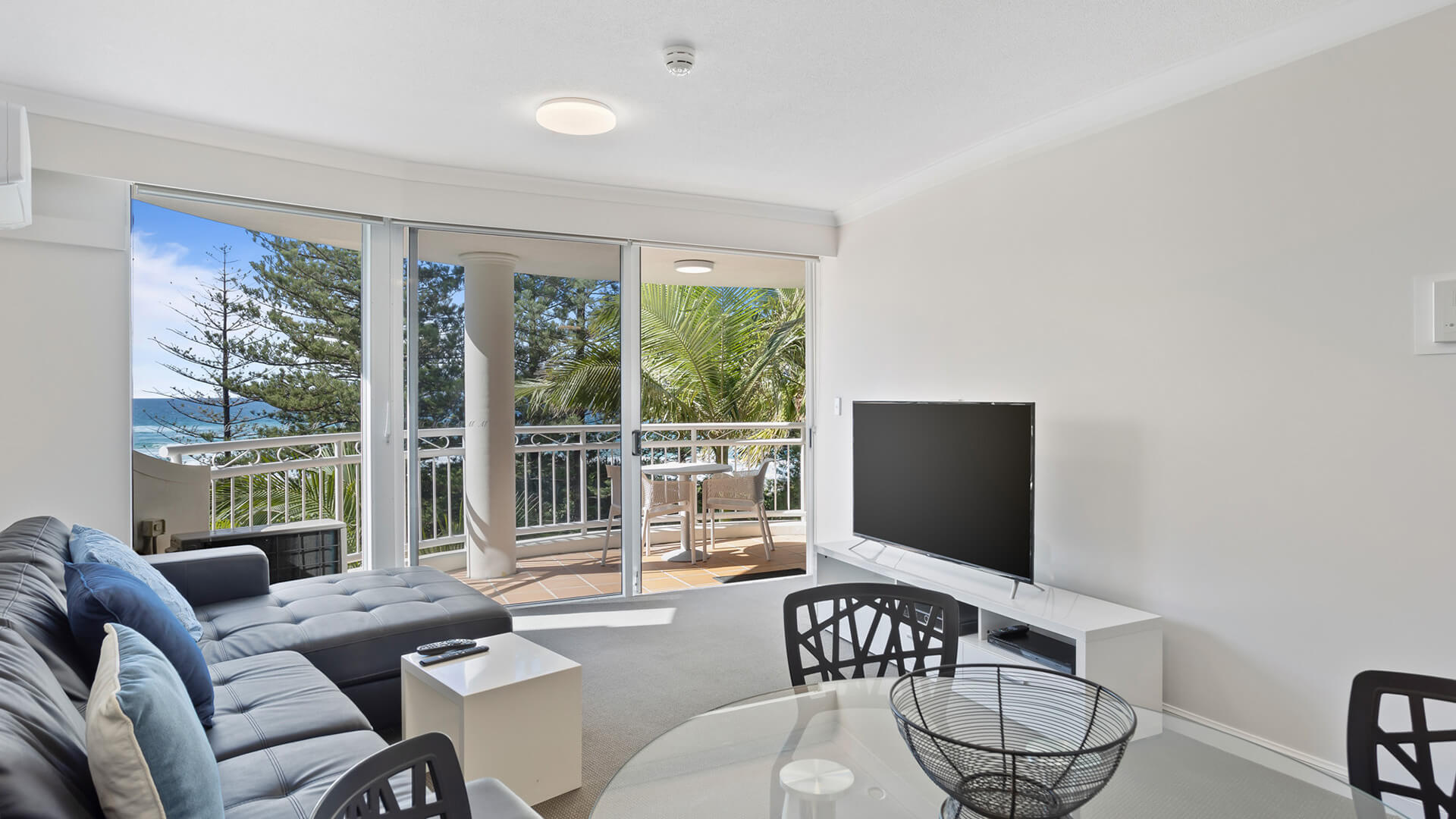 Spacious living area with ocean glimpses and balcony access.