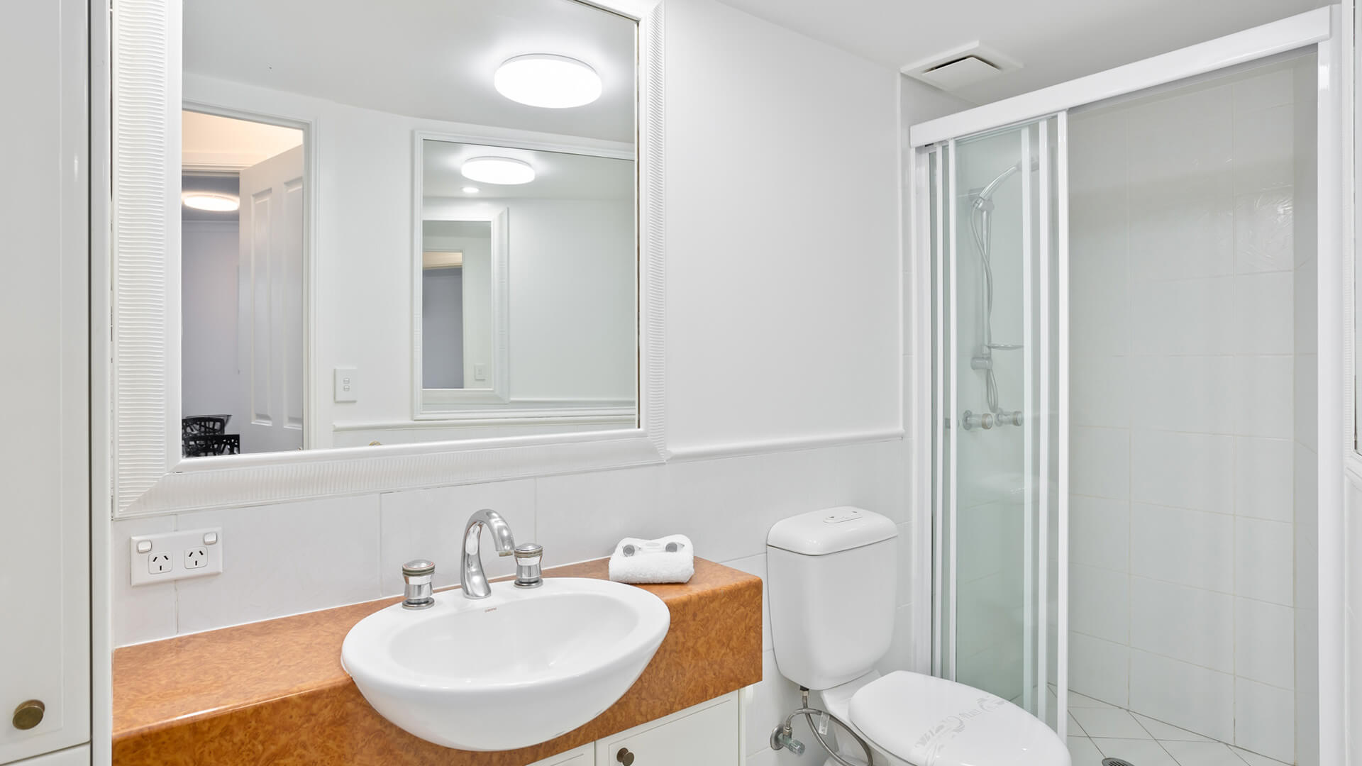 Bathroom featuring a shower, vanity, toilet, and large mirror.