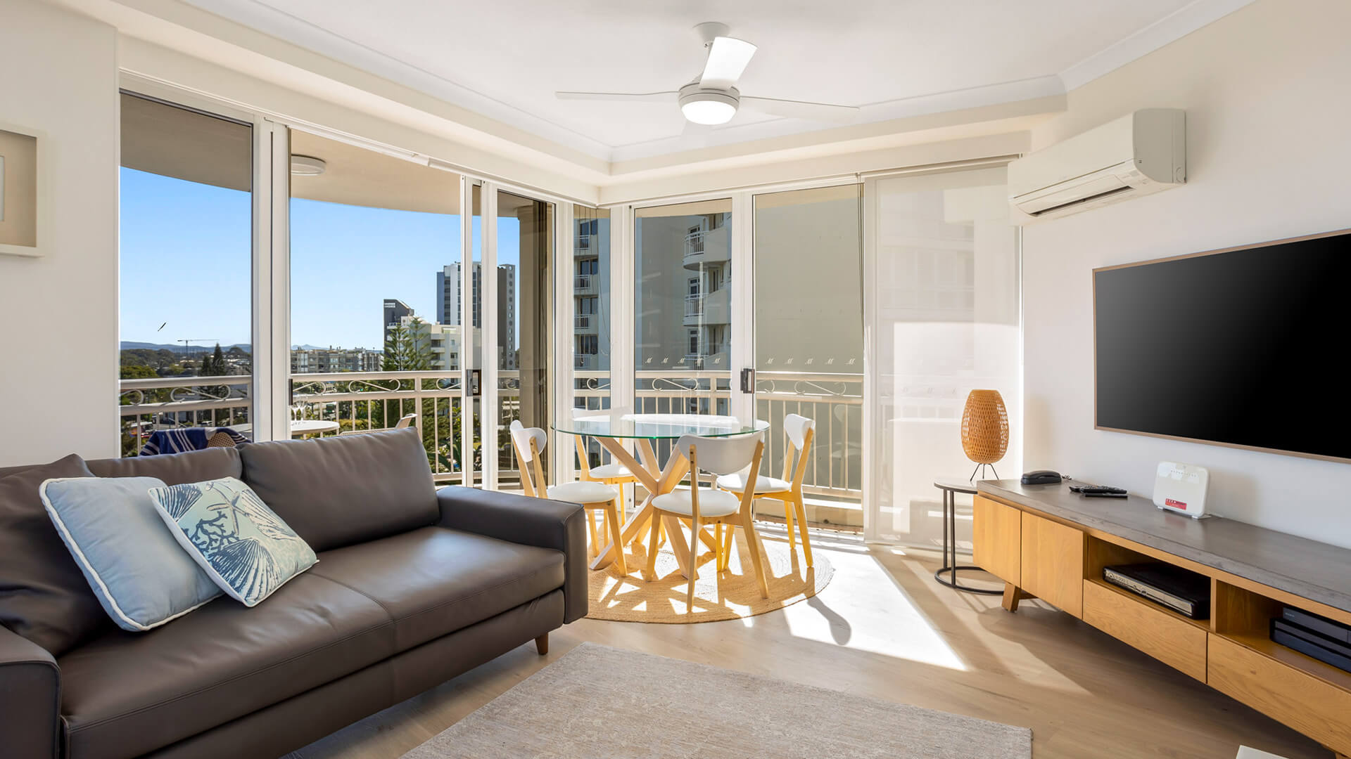 Bright living area with balcony access and smart TV.