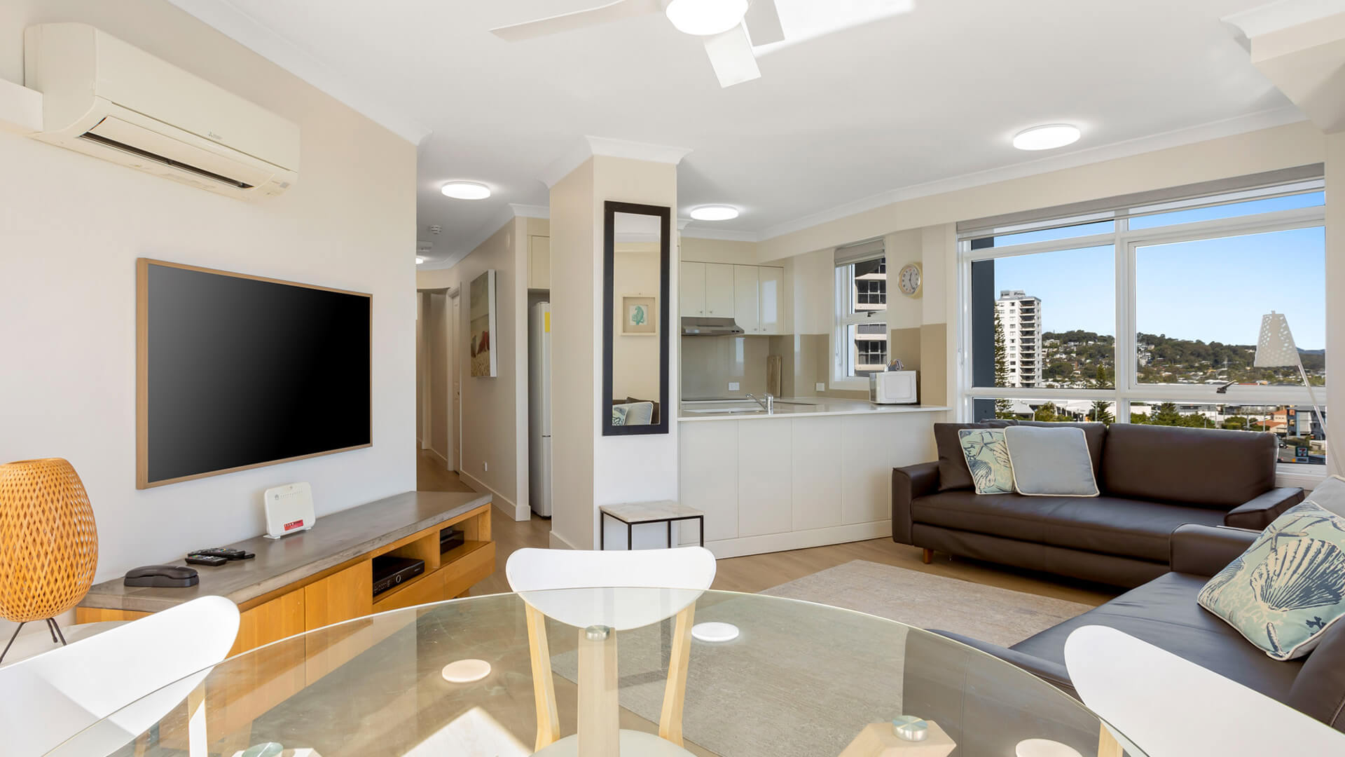 Spacious living and dining area with modern furnishings and large windows offering city views.