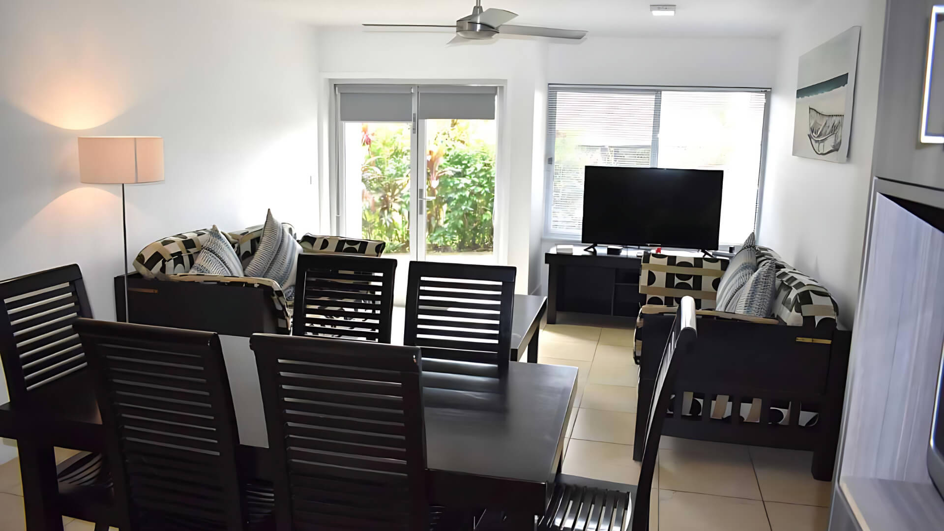 Dining and living area of Standard 2 Bedroom 1 Bathroom Apartment at ULTIQA Fiji with TV and sofas.
