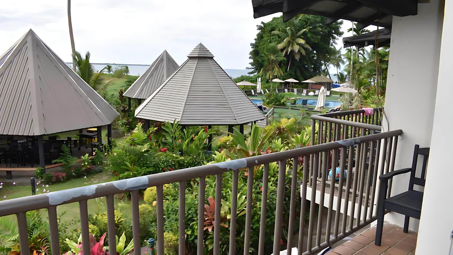 Balcony view of lush gardens, thatched pavilions, and pool area at ULTIQA Fiji.