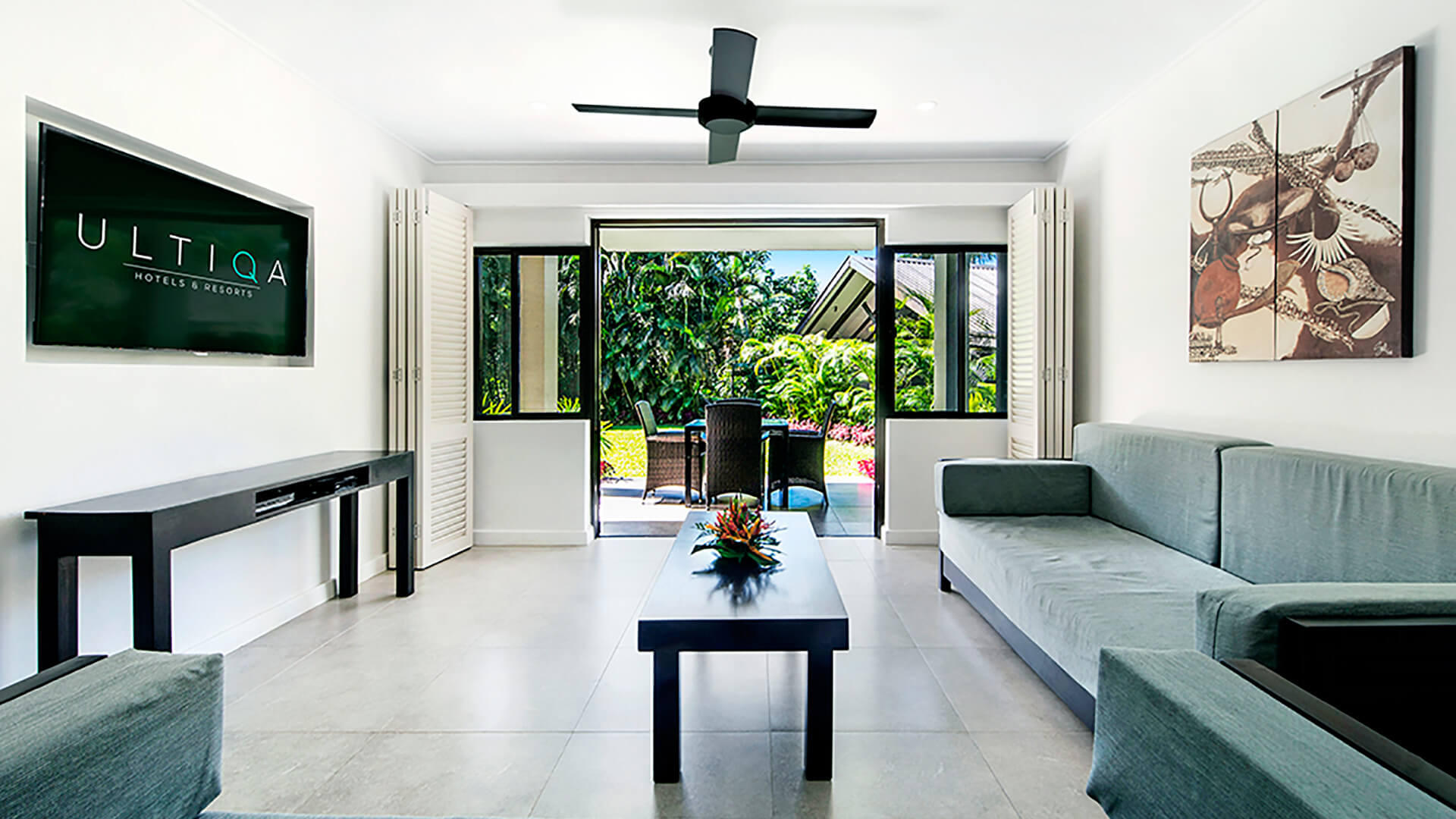Living room in 2 Bedroom Apartment at ULTIQA Fiji Palms with sofas, TV, and patio opening to tropical gardens.