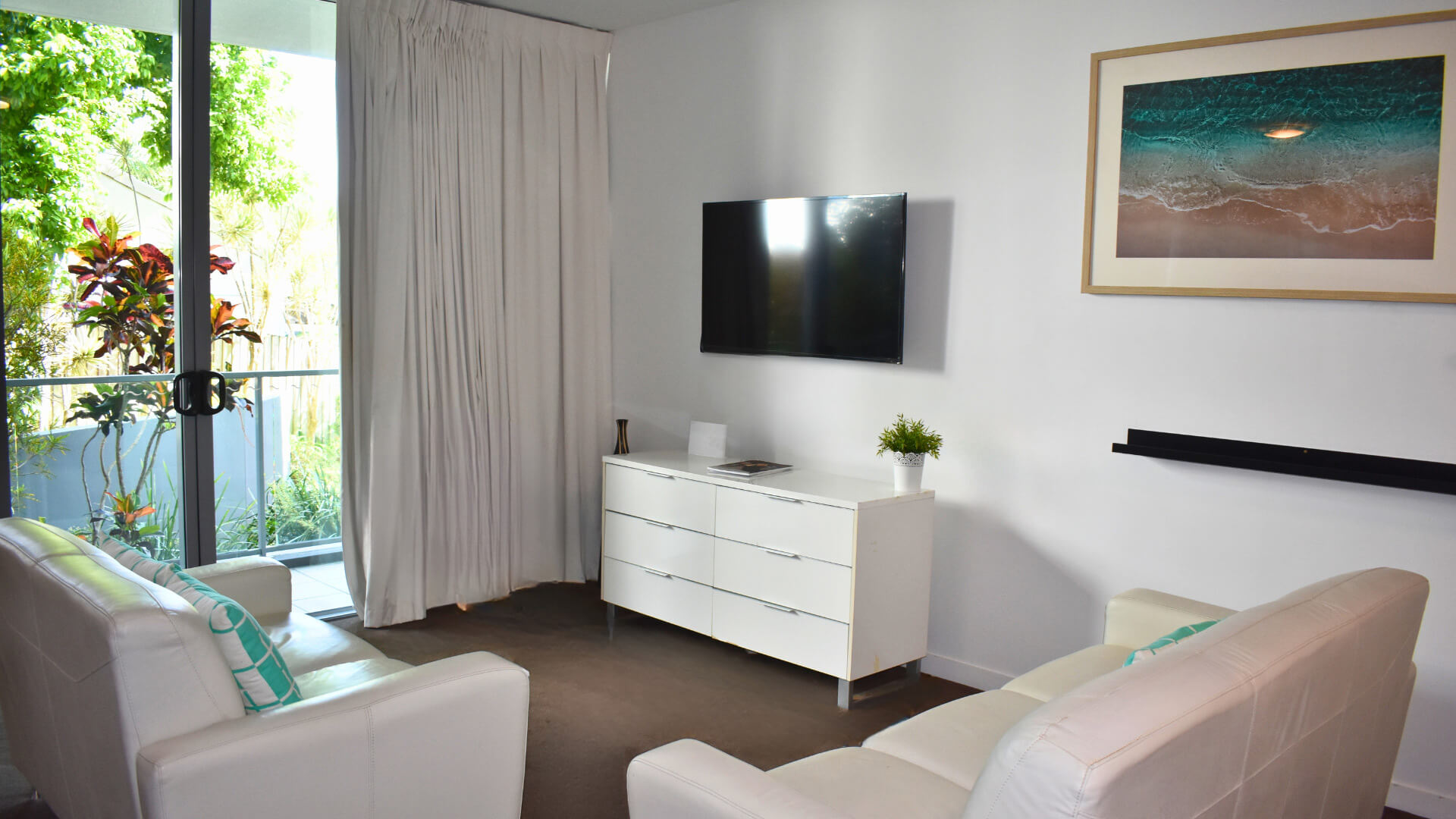 Studio living area at ULTIQA Freshwater Point Resort with TV, white furnishings, and balcony access.