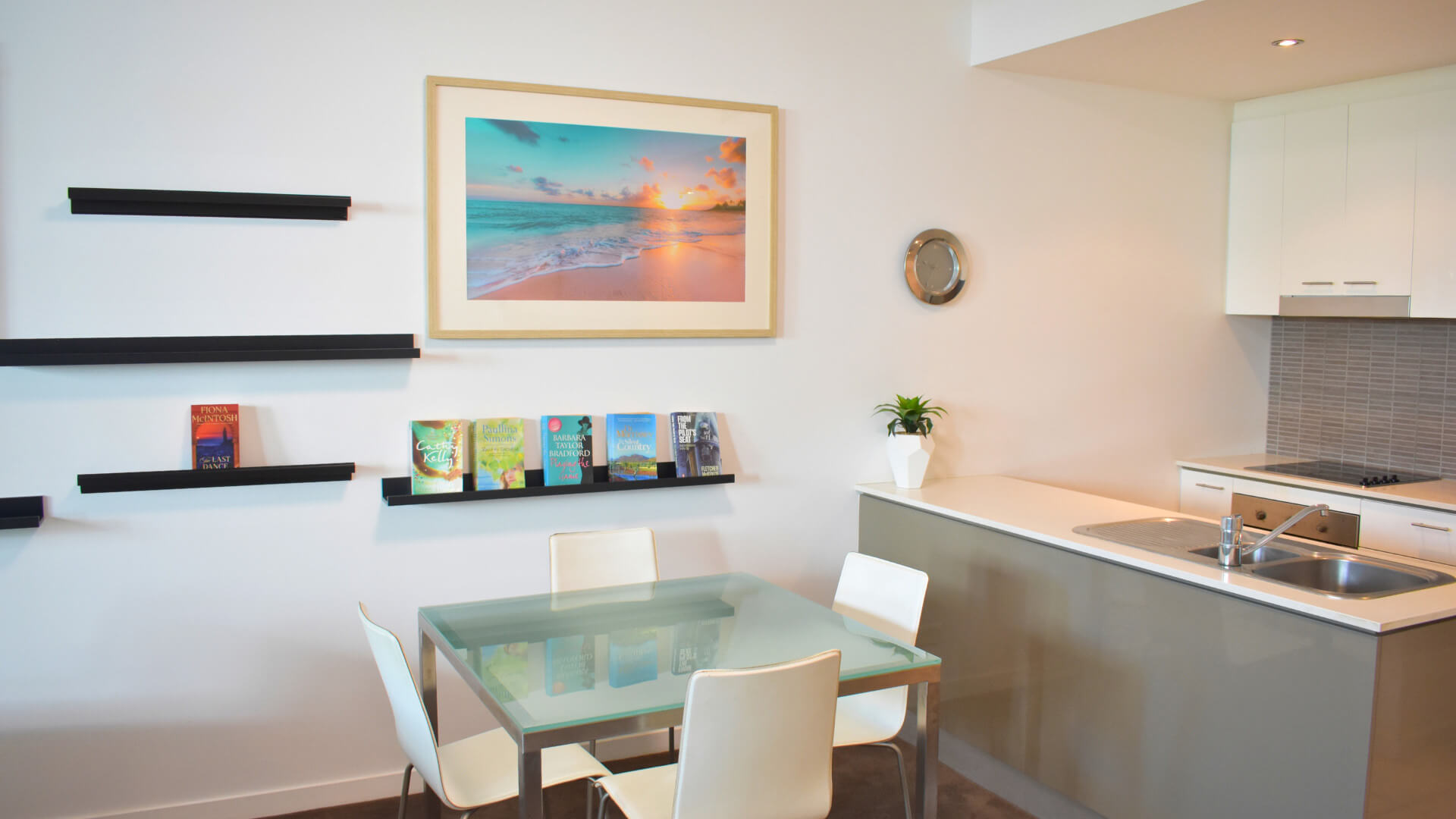 Studio kitchenette and dining area at ULTIQA Freshwater Point Resort with modern decor and books on display.