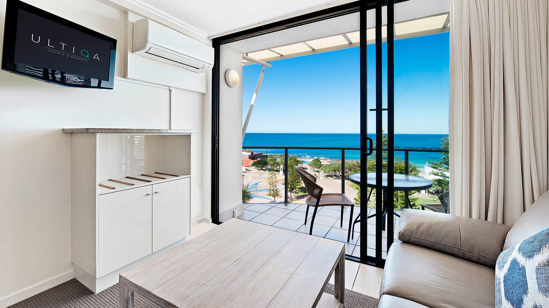 Lounge area with sofa, coffee table, and ocean-view balcony at ULTIQA Shearwater Resort.