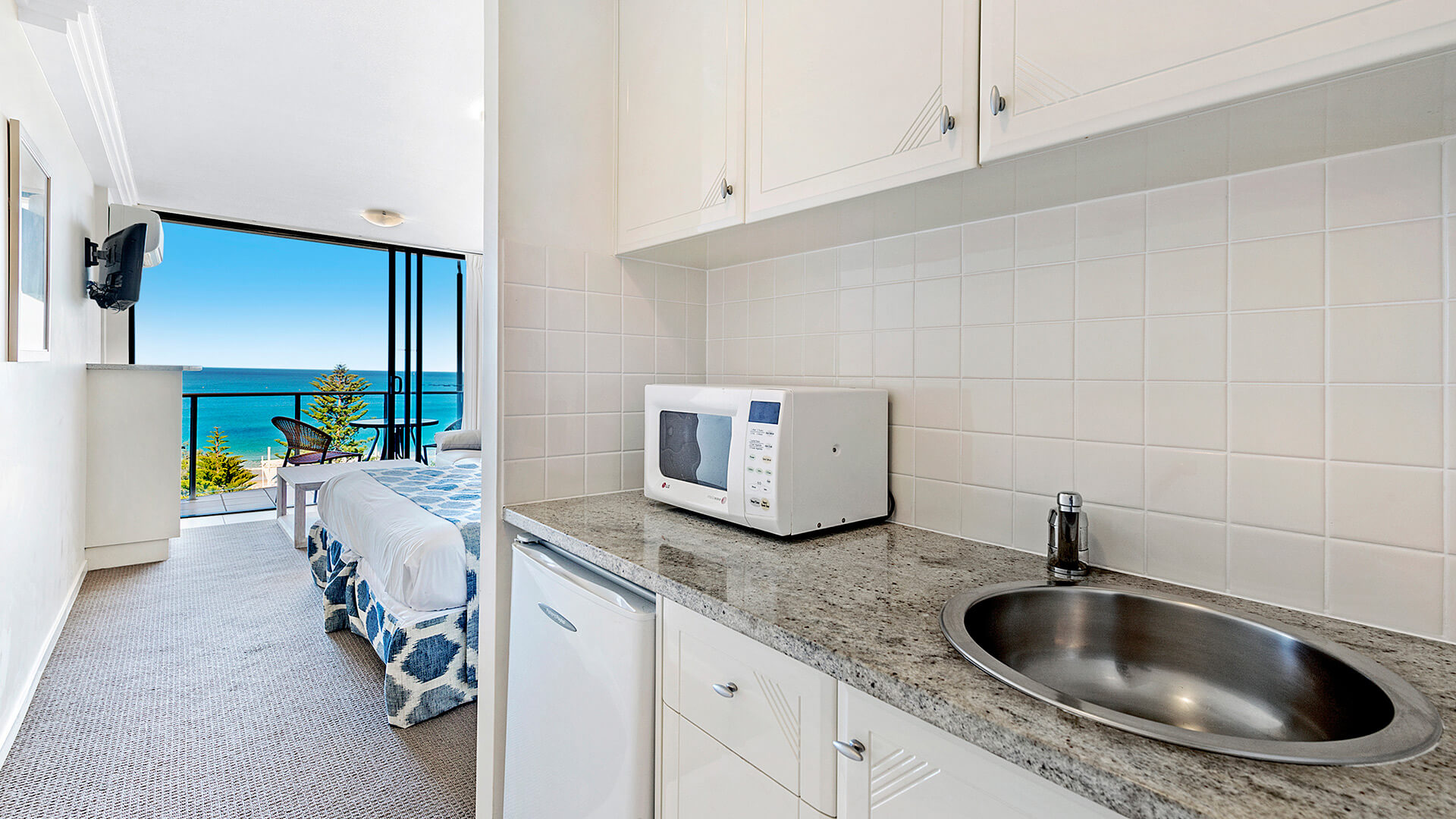 Kitchenette with microwave, sink, and mini fridge in a Studio at ULTIQA Shearwater Resort, overlooking the ocean.
