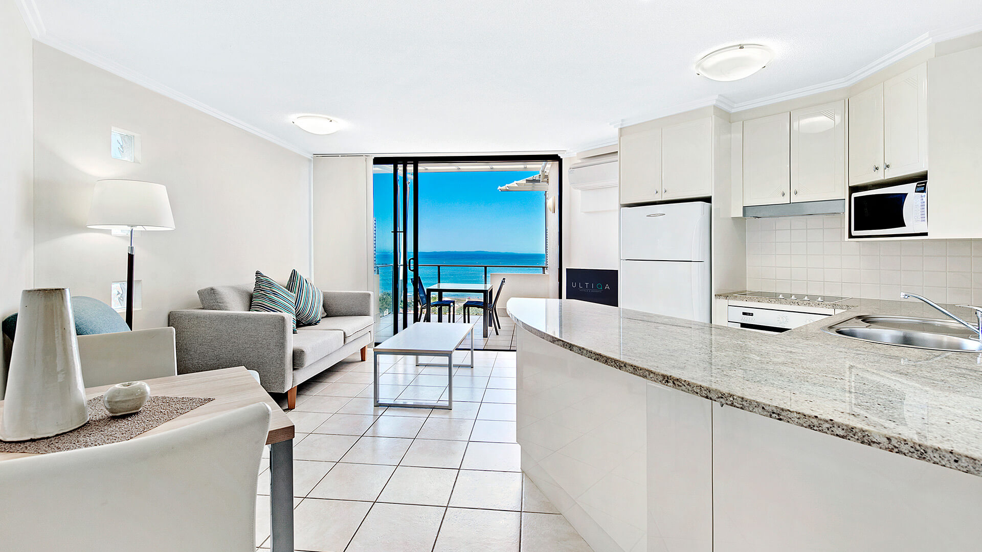 Open-plan living, dining, and kitchen area with ocean views in 1 Bedroom Apartment at ULTIQA Shearwater Resort.