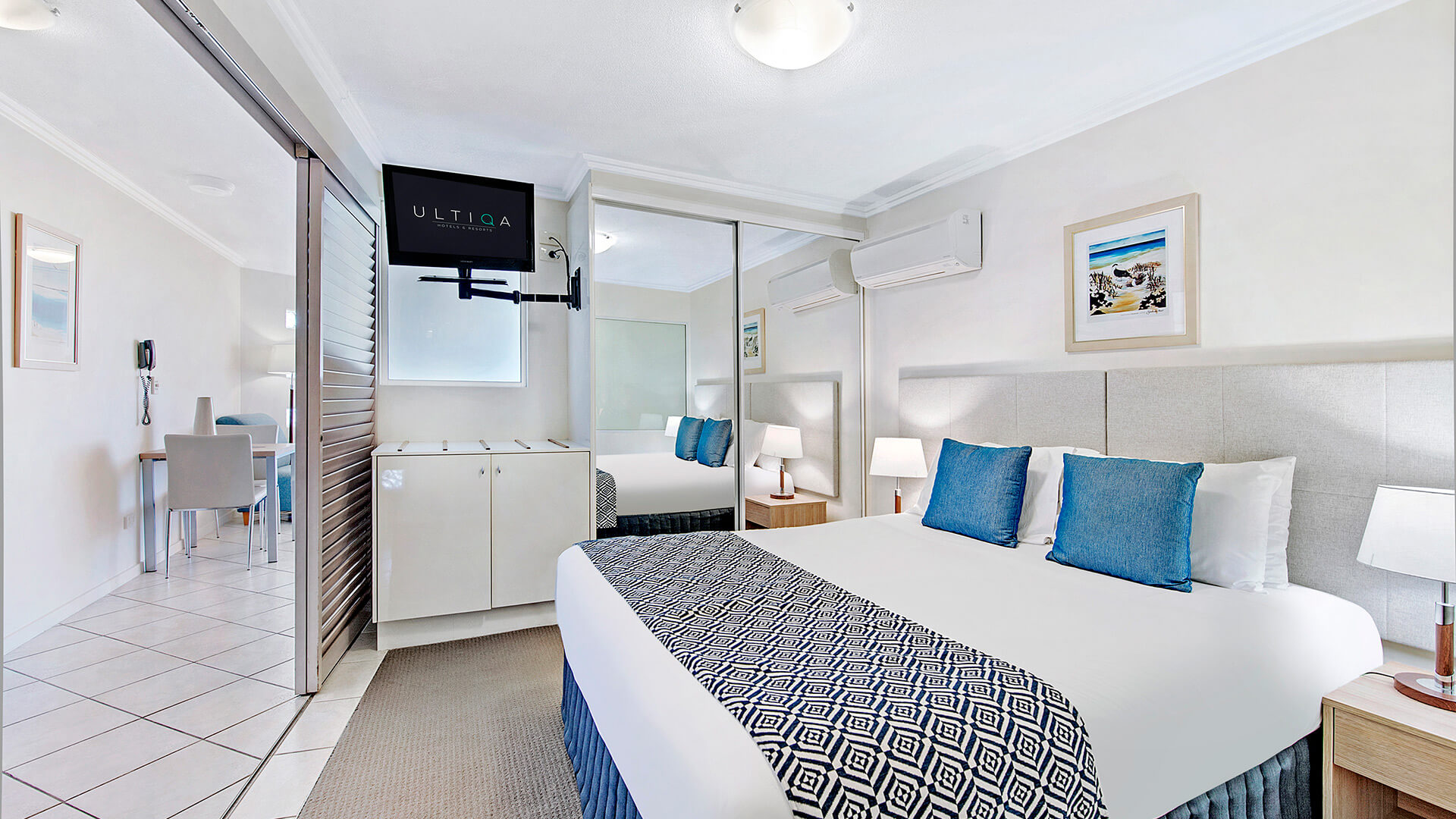 Bedroom with king bed, mirrored wardrobe, and TV in 1 Bedroom Apartment at ULTIQA Shearwater Resort.