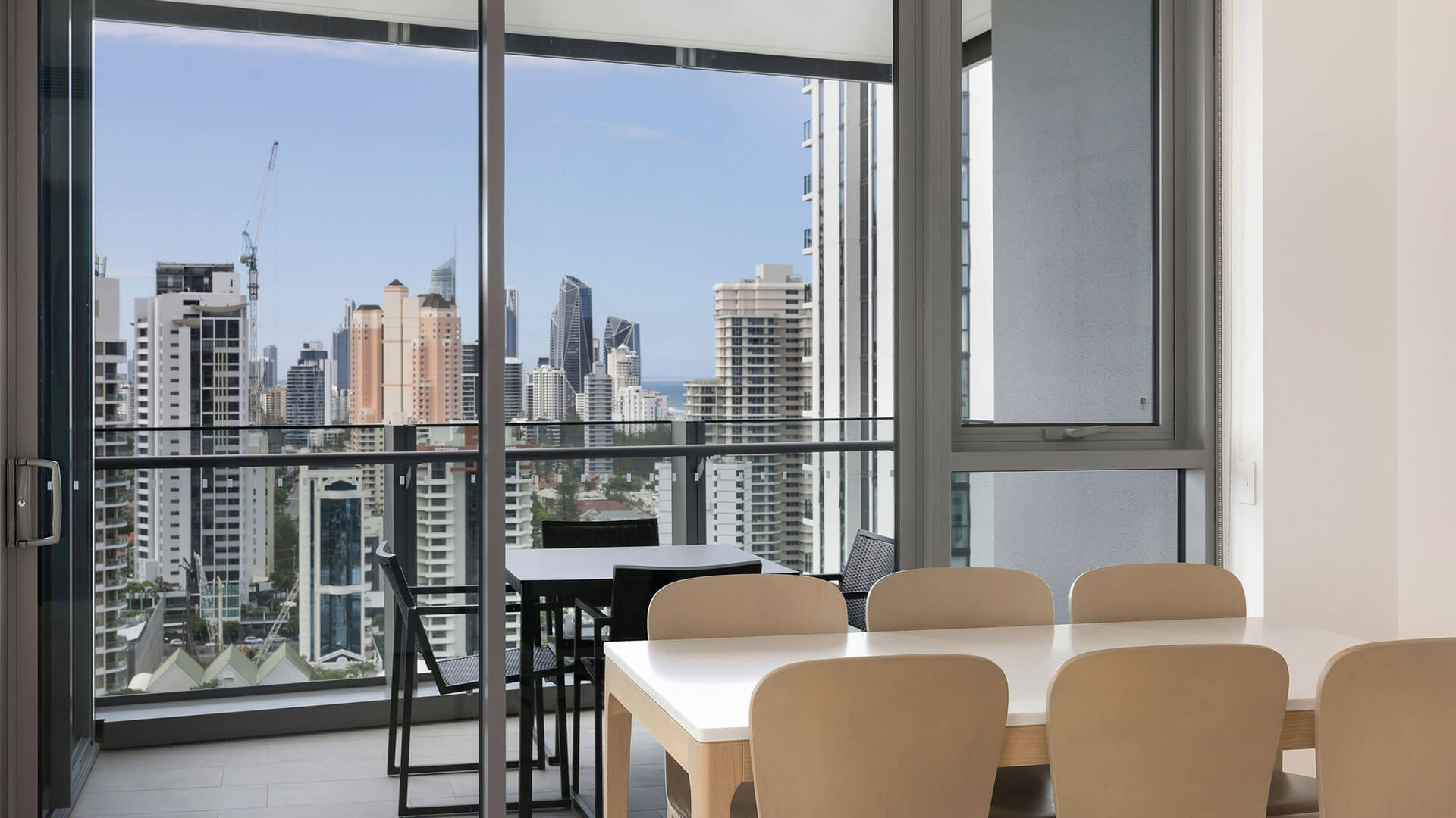 Dining table with seating for six and balcony with city views in the 2 Bedroom Skyhome at ULTIQA Signature at Broadbeach.