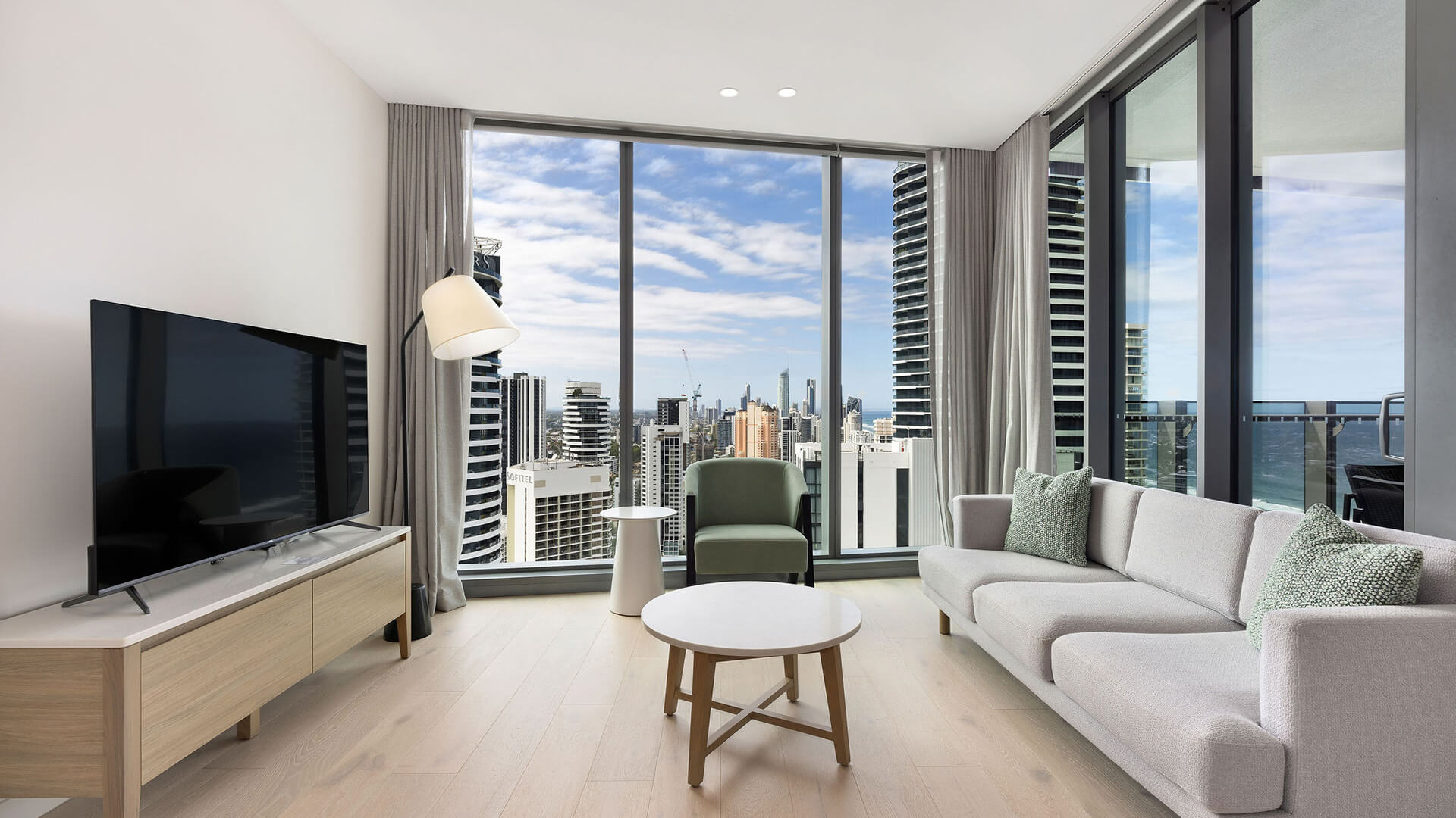 Spacious living area with floor-to-ceiling windows and panoramic city views in the 2 Bedroom Skyhome at ULTIQA Signature at Broadbeach.
