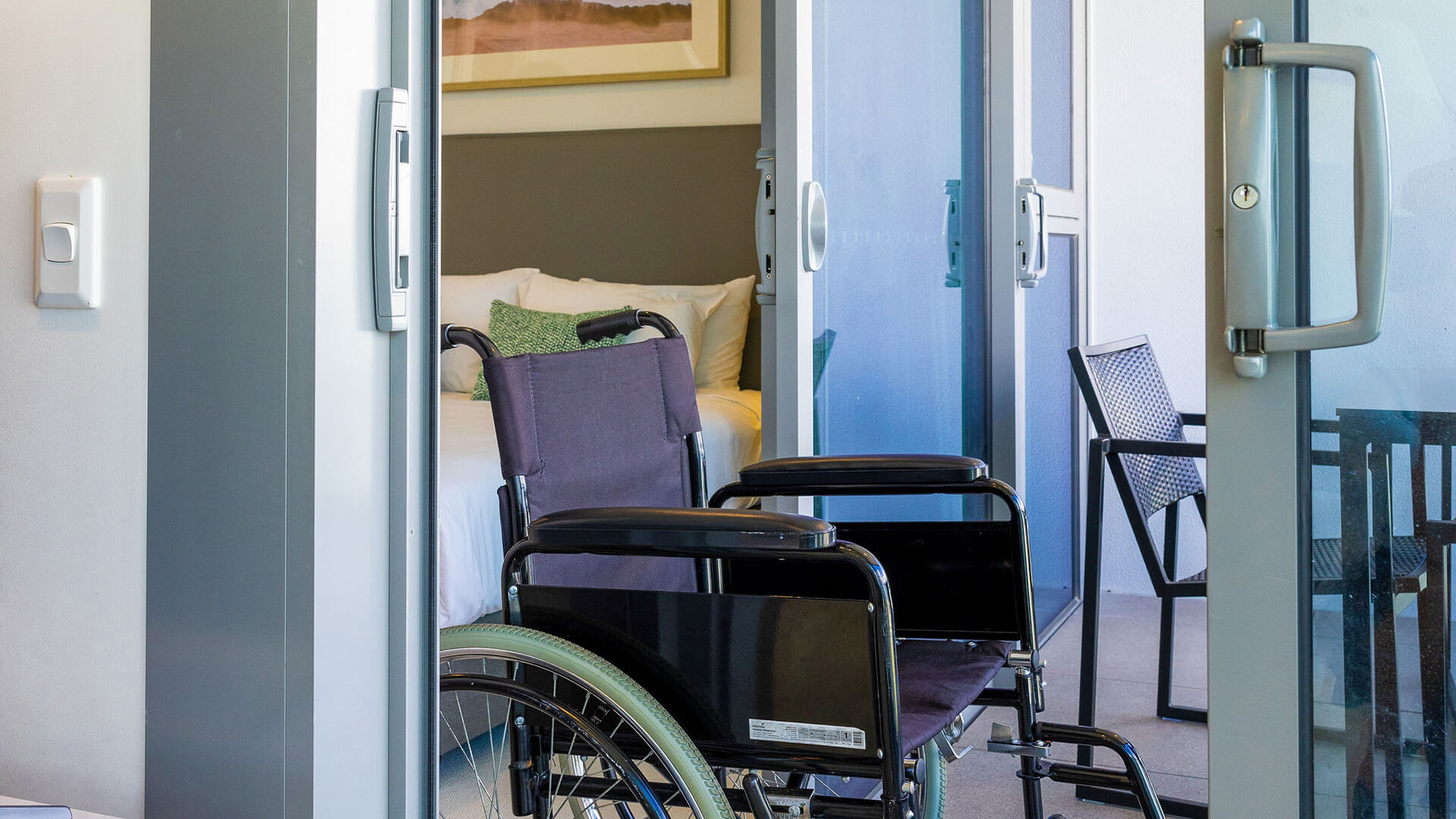 Wheelchair on balcony outside bedroom in 2 Bedroom Accessible Suite at ULTIQA Signature at Broadbeach.