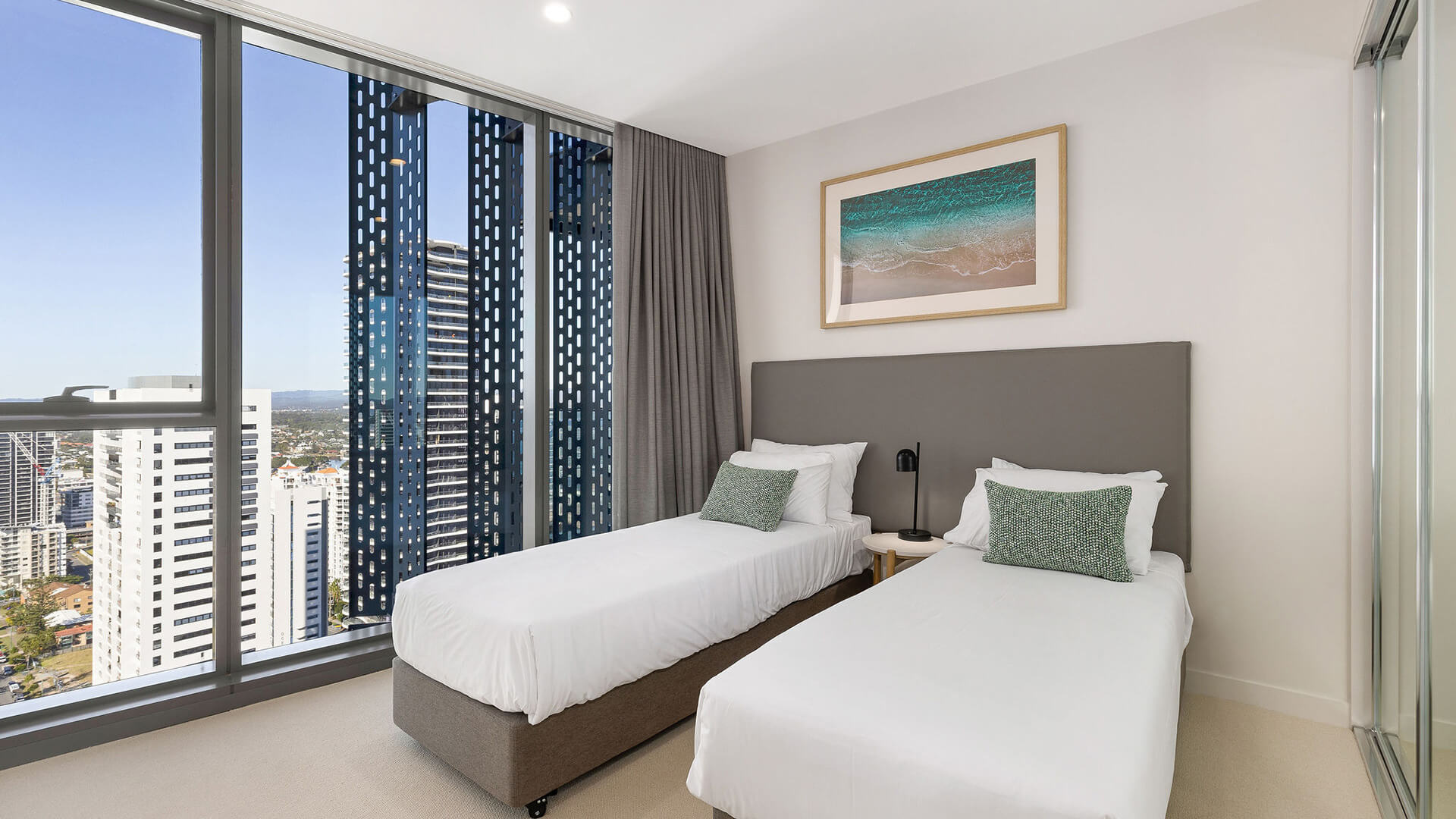 Second bedroom with two single beds and city views in the 2 Bedroom Ocean View Suite at ULTIQA Signature at Broadbeach.