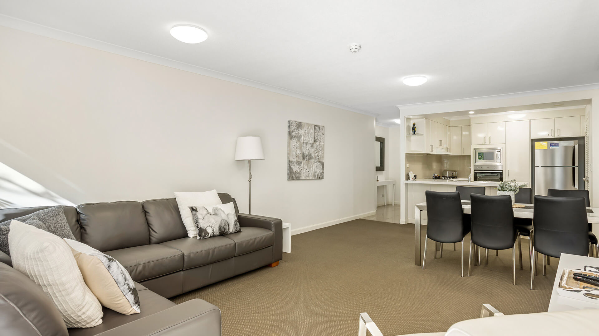 Open-plan lounge, dining, and kitchen area in 2 Bedroom Garden View Apartment at ULTIQA Burleigh Mediterranean Resort.