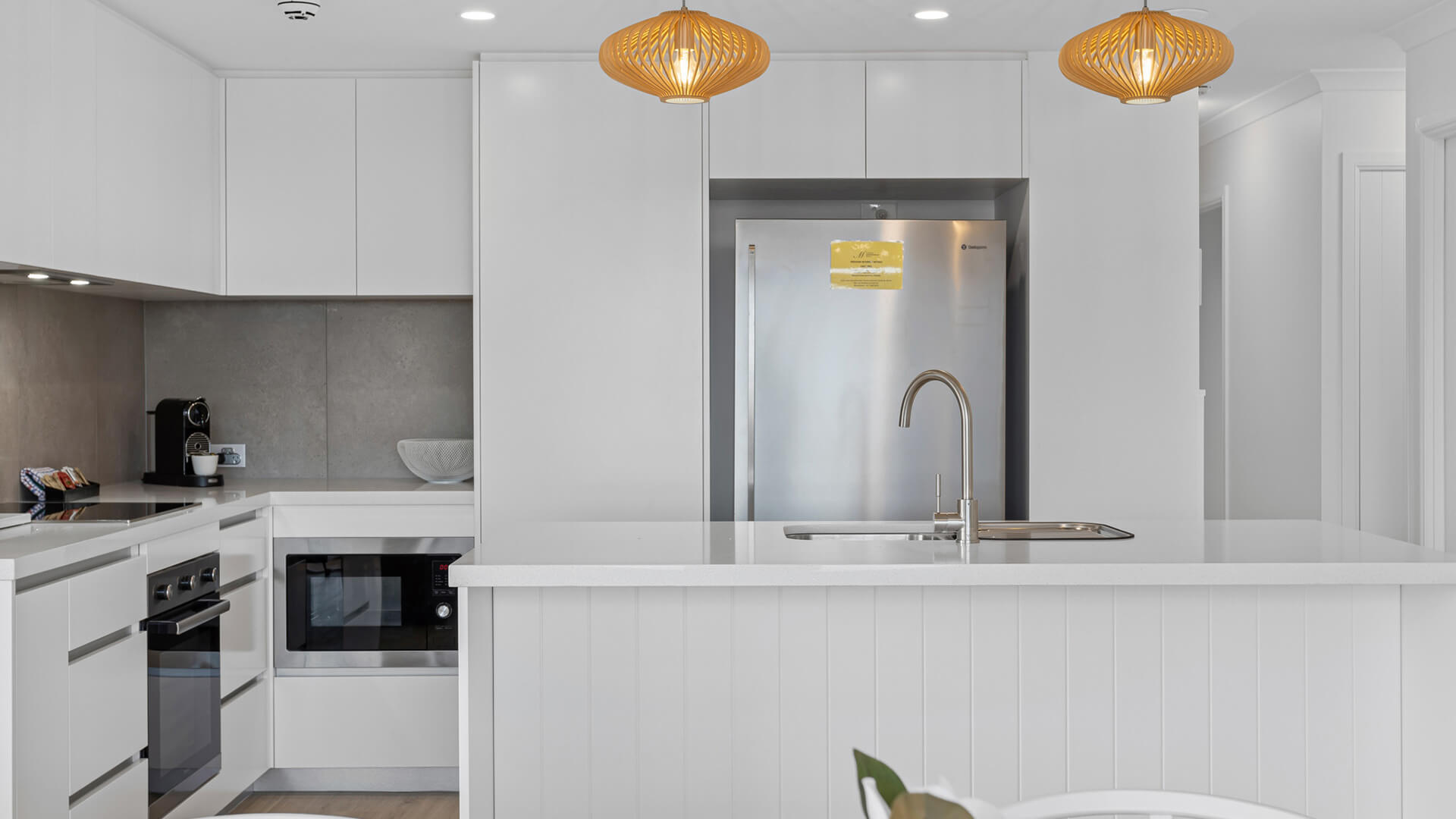 Modern kitchen with island bench and pendant lighting in 3 Bedroom Superior Ocean View Apartment at ULTIQA Burleigh Mediterranean Resort.