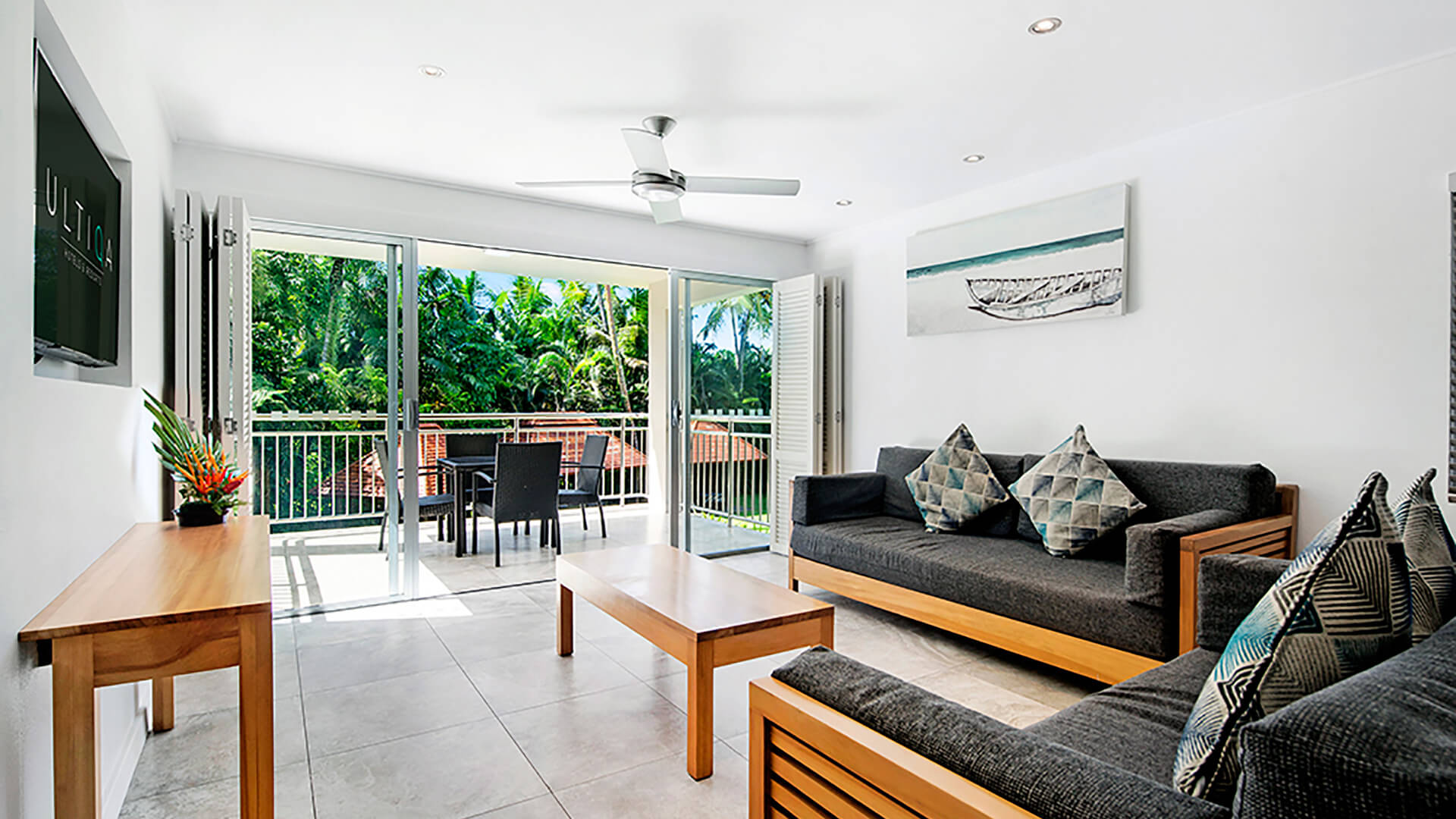 Spacious living room in 2 Bedroom Deluxe Apartment at ULTIQA Fiji with modern furnishings, balcony, and tropical garden views.