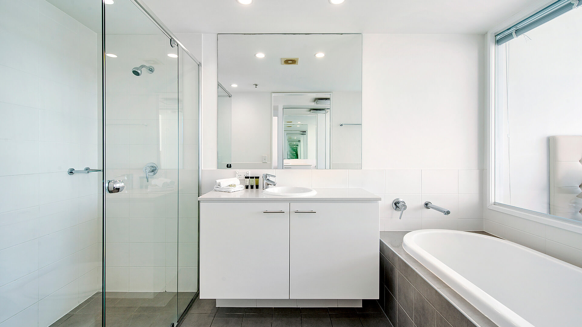 Bathroom in the 1 Bedroom Apartment at ULTIQA Freshwater Point Resort featuring a walk-in shower, vanity, and spa bath.