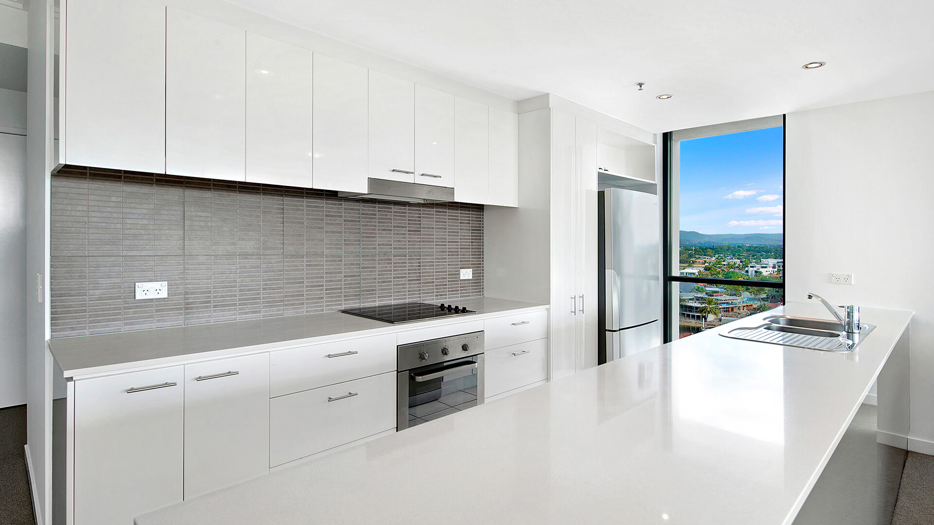 Contemporary kitchen with sleek cabinetry, stone benchtop, and hinterland views in the 3 Bedroom Apartment at ULTIQA Freshwater Point Resort.