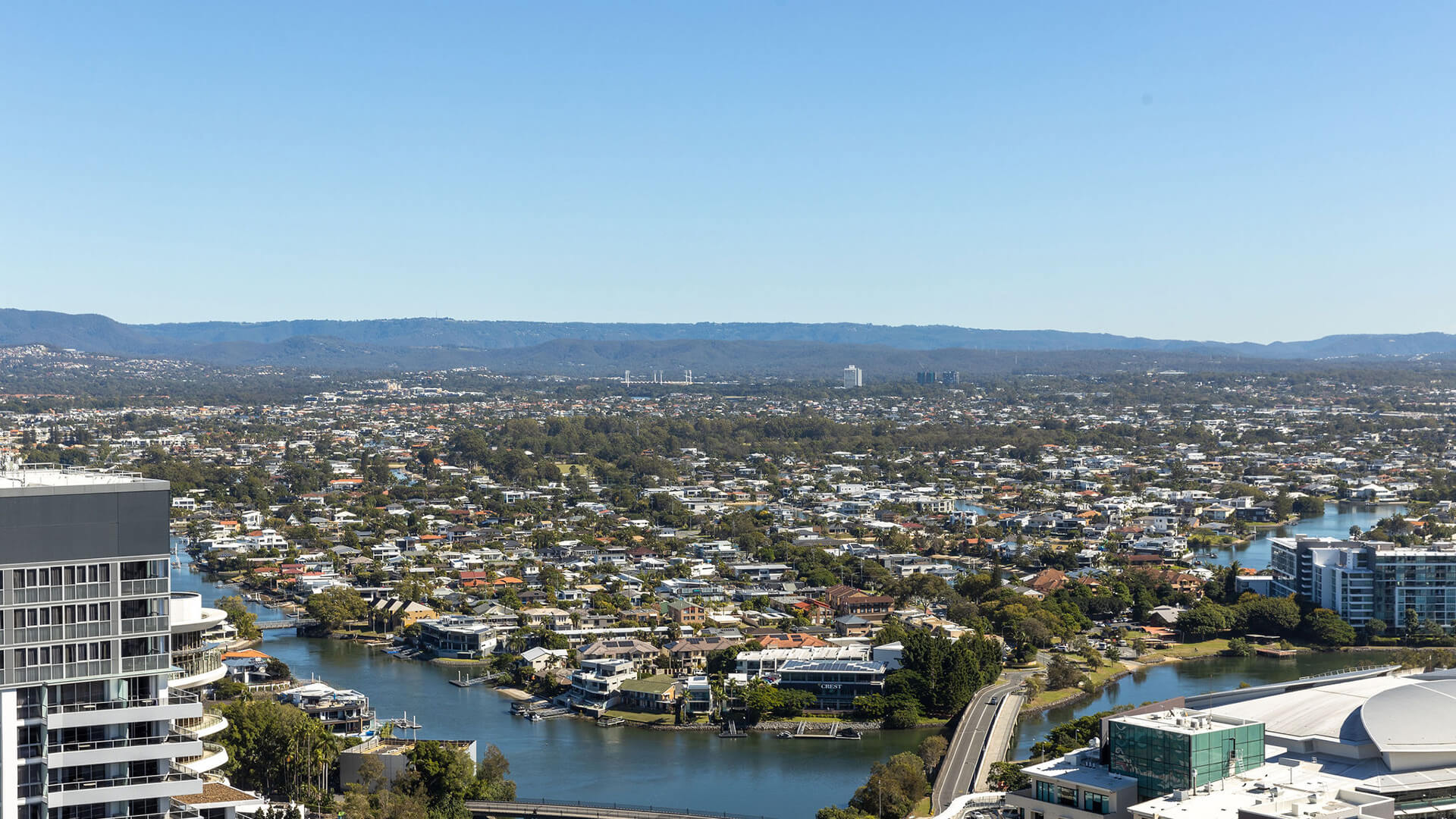 View from the 3 Bedroom Ocean View Suite at ULTIQA Signature at Broadbeach, showing cityscape, river, bridges, and distant hills under a clear blue sky.